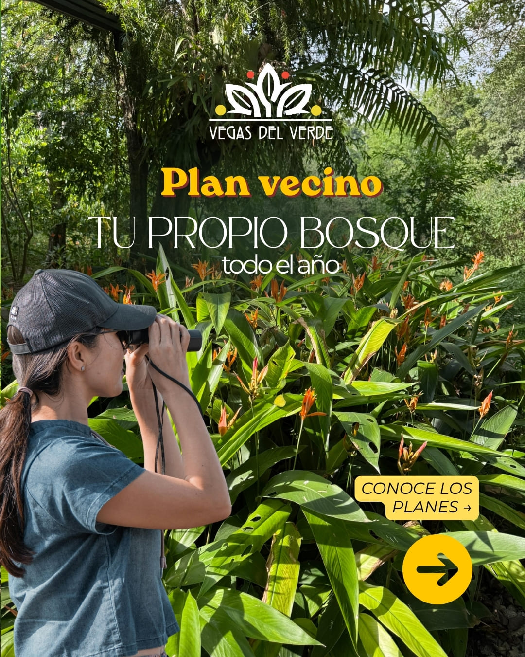 Una visitante observa el jardín con binóculos, entre heliconias y follaje espeso.